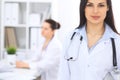 Brunette female doctor on the background of colleagues talking to each other in hospital. Physician is ready to help Royalty Free Stock Photo