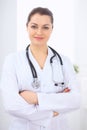 Brunette female doctor on the background of colleagues talking to each other in hospital. Physician is ready to help Royalty Free Stock Photo