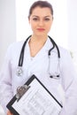 Brunette female doctor on the background of colleagues talking to each other in hospital. Physician is ready to help Royalty Free Stock Photo