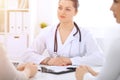 Brunette female doctor talking to patient at hospital office. Physician says about medical exams results for choosing Royalty Free Stock Photo