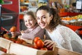 Brunette female with a little girl considering tomatoes at store Royalty Free Stock Photo