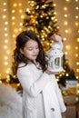 A brunette gilr in front of fur-tree and fireplace with candles and gifts. A girl dreaming. New year`s eve. Christmas .