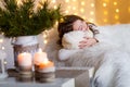 A brunette gilr in front of fur-tree and fireplace with candles and gifts. A girl dreaming. New year`s eve. Christmas .