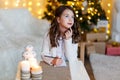 A brunette gilr in front of fur-tree writing a letter to santa claus. A girl dreaming. New year`s eve. Christmas