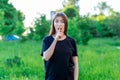 The brunette girl in a black T-shirt. Summer in park in the fresh air. Hand gesture do not talk. He covers his mouth Royalty Free Stock Photo