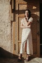 brunette girl in dress poses at an ancient door