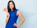 Brunette girl dressed in blue smiling, holding heart shaped red candy in her arm. Saint Valentine`s Day concept Royalty Free Stock Photo