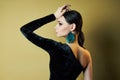 Brunette girl dressed in a chic black evening dress with an open shoulder, beautiful big earrings in her ears. Perfect smile, Royalty Free Stock Photo