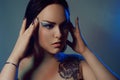 Brunette girl with a flower tattoo on her shoulder and tunnels in her ears in beautiful blue light. Woman with blue make-up, Royalty Free Stock Photo