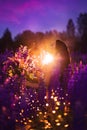 A brunette girl in a gradient haute couture dress standing among a blooming lupine field