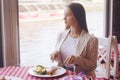 Brunette girl with long hair in a restaurant on ship on the background of the river. Girl tries salmon with rice. Girl eats applia Royalty Free Stock Photo