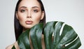 Brunette girl in palm leaves. Beautiful young woman with Make-up