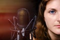 Brunette girl for a professional microphone, close-up. Professional record of the singer in the Studio. Female vocalist on black Royalty Free Stock Photo