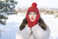 Brunette girl in red knitted hat and mittens in winter outdoors. Little red riding hood