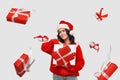 Brunette girl in a red sweater and Santa Claus hat holding white giftbox with red ribbon Royalty Free Stock Photo