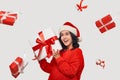 Brunette girl in a red sweater and Santa Claus hat holding white giftbox with red ribbon Royalty Free Stock Photo