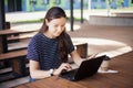 A brunette girl sits behind wooden desk, looks at a laptop monitor, smiles, laughs, talks online, drinks coffee, works. Royalty Free Stock Photo