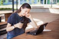 A brunette girl sits behind wooden desk, looks at a laptop monitor, smiles, laughs, talks online, drinks coffee, works. Royalty Free Stock Photo