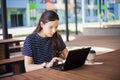 A brunette girl sits behind wooden desk, looks at a laptop monitor, smiles, laughs, talks online, drinks coffee, works. Royalty Free Stock Photo