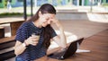 A brunette girl sits behind wooden desk, looks at a laptop monitor, smiles, laughs, talks online, drinks coffee, works. Royalty Free Stock Photo