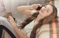 Brunette girl sitting on carpet near sofa and talking by phone, horizontal Royalty Free Stock Photo