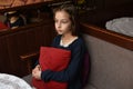 Scared young woman is watching tv. Brunette girl is sitting on the couch with red pillow