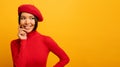 Brunette girl smiles with red hat and cardigan. Emotional and joyful expression. Yellow background