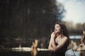 Brunette girl stands by the tree near the water Royalty Free Stock Photo