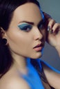 Brunette girl with tunnels in her ears in a beautiful blue light. Woman with blue make-up, fashionable blue arrows over the eyelid Royalty Free Stock Photo