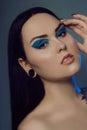 Brunette girl with tunnels in her ears in a beautiful blue light. Woman with blue make-up, fashionable blue arrows over the eyelid Royalty Free Stock Photo