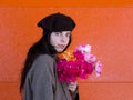 Brunette girl wearing beret and coat holding colourful bouquet