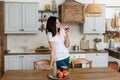 Brunette girl in a white T-shirt in the kitchen eat an apple. Royalty Free Stock Photo