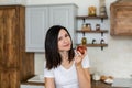 Brunette girl in a white T-shirt in the kitchen eat an apple Royalty Free Stock Photo