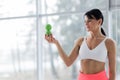 A brunette girl in a white top and coral leggings holds a massage ball in her hands