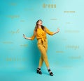 Brunette girl with a yellow clothes walks over a cyan background. Concept of fashion and shopping with joyful expression