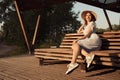 Brunette with glasses sitting on a park bench. Sunset light, evening. young woman in casual dress Royalty Free Stock Photo