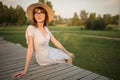 Brunette with glasses sitting on a park bench. Sunset light, evening. young woman in casual dress Royalty Free Stock Photo