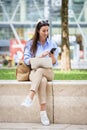 Brunette haired business woman sitting on a bench in the city and using a laptop and smartphone for work Royalty Free Stock Photo