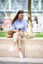 Brunette haired woman sitting on a bench in the city and using a laptop and smartphone for work Royalty Free Stock Photo