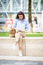 Brunette haired woman sitting on a bench in the city and using a laptop for work Royalty Free Stock Photo