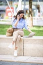 Brunette haired woman sitting on a bench in the city and using a laptop and smartphone for work Royalty Free Stock Photo