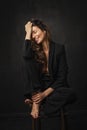 Brunette haired woman wearing black blazer and posing against at isolated dark background Royalty Free Stock Photo