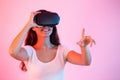 Brunette with headset pointing her finger in virtual reality