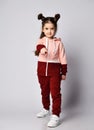 Brunette kid girl in modern fashion pink brown sportwear pointing her finger at us