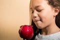 Brunette latin kid looking with desire at a red candy apple on a isolated orange background. Little girl bites her lips in front Royalty Free Stock Photo