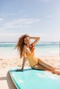 Brunette laughing lady posing at beach after surfing. Magnificent girl in orange swimwear sitting o