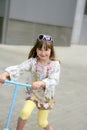 Brunette little girl with scooter in the city