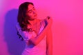 Brunette with long curled hair dancing in neon. A girl with professional makeup in red and blue light posing. Sexy model in a Royalty Free Stock Photo