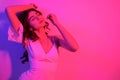 Brunette with long curled hair dancing in neon. A girl with professional makeup in red and blue light posing. Sexy model in a Royalty Free Stock Photo