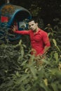 A brunette man of model appearance in a red shirt next to an abandoned telephone booth Royalty Free Stock Photo